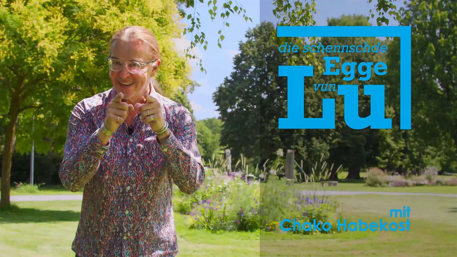 Chako Habekost gestikuliert in einem Park, daneben der Titel „Die schennschde Egge vun Lu“