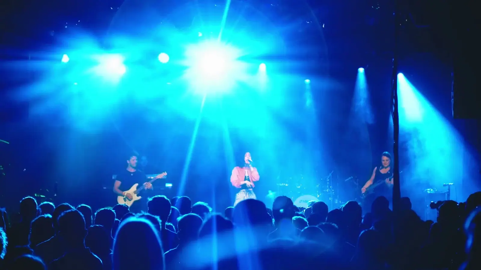 Band auf einer Bühne im blauen Scheinwerferlicht vor Publikum