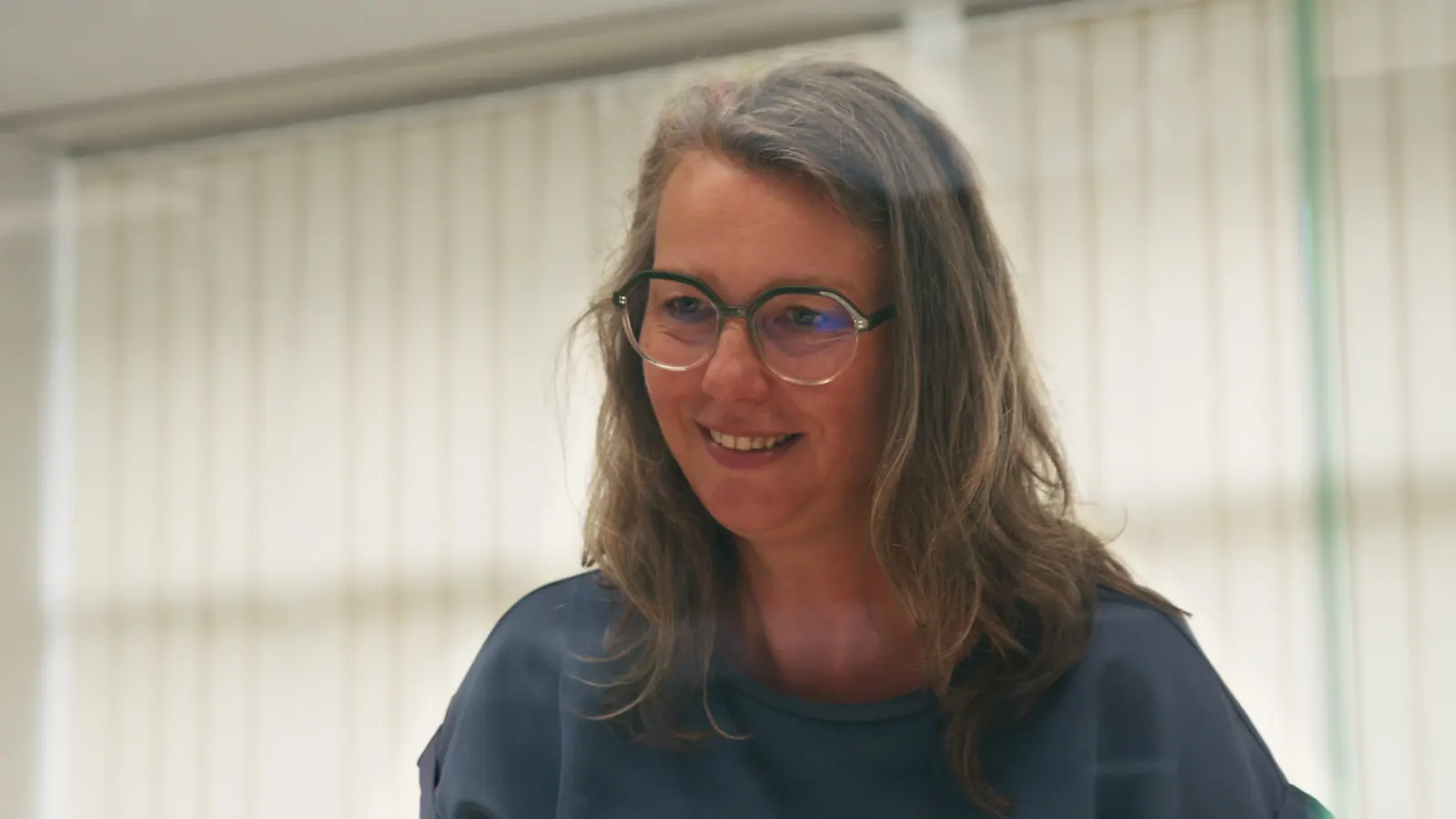 Frau mit Brille lächelt in einem hellen Büro