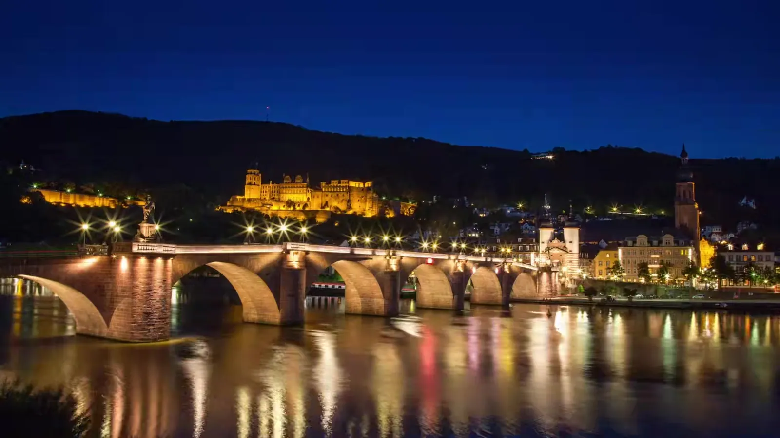 Alte Brücke und beleuchtetes Heidelberger Schloss bei Nacht am Neckar