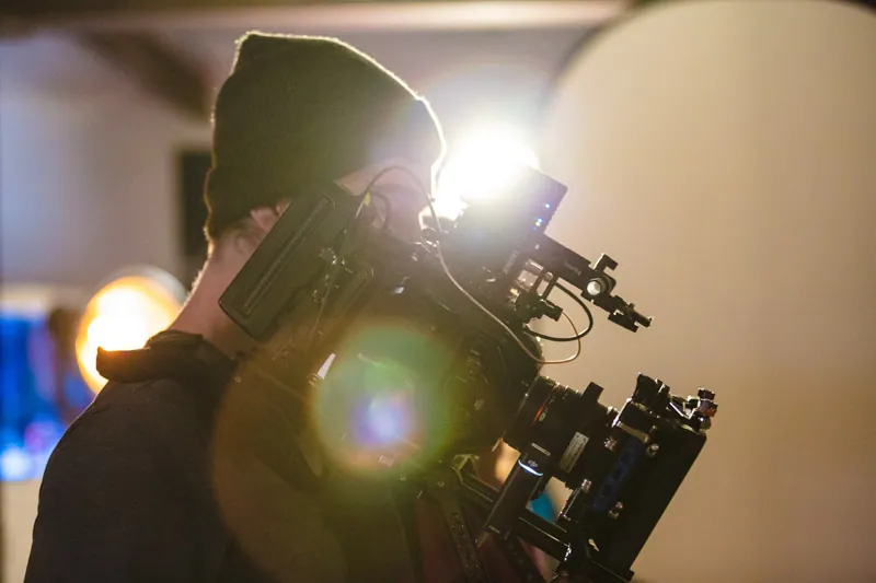 Kameramann mit Cinema-Kamera im warmen Gegenlicht am Set